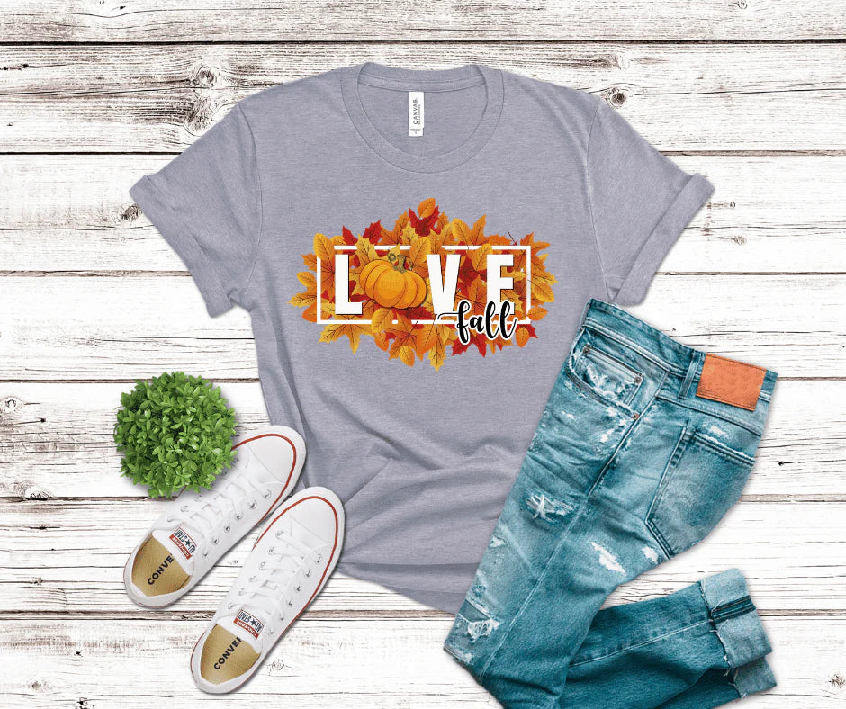 Gray t-shirt with 'LOVE fall' design, white sneakers, and blue jeans on a wooden surface